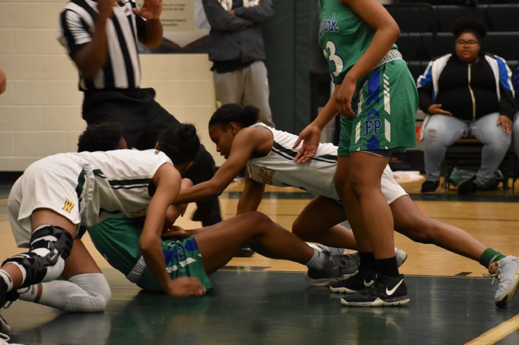 Players scrap on the floor for a loose ball during the hard-fought district contest.